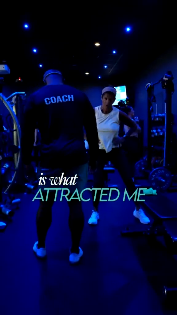 Fitness coach training a female client in a modern gym with blue ambient lighting.